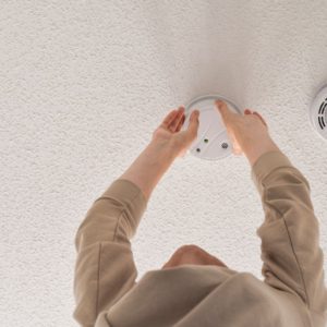 woman reaching for smoke alarm