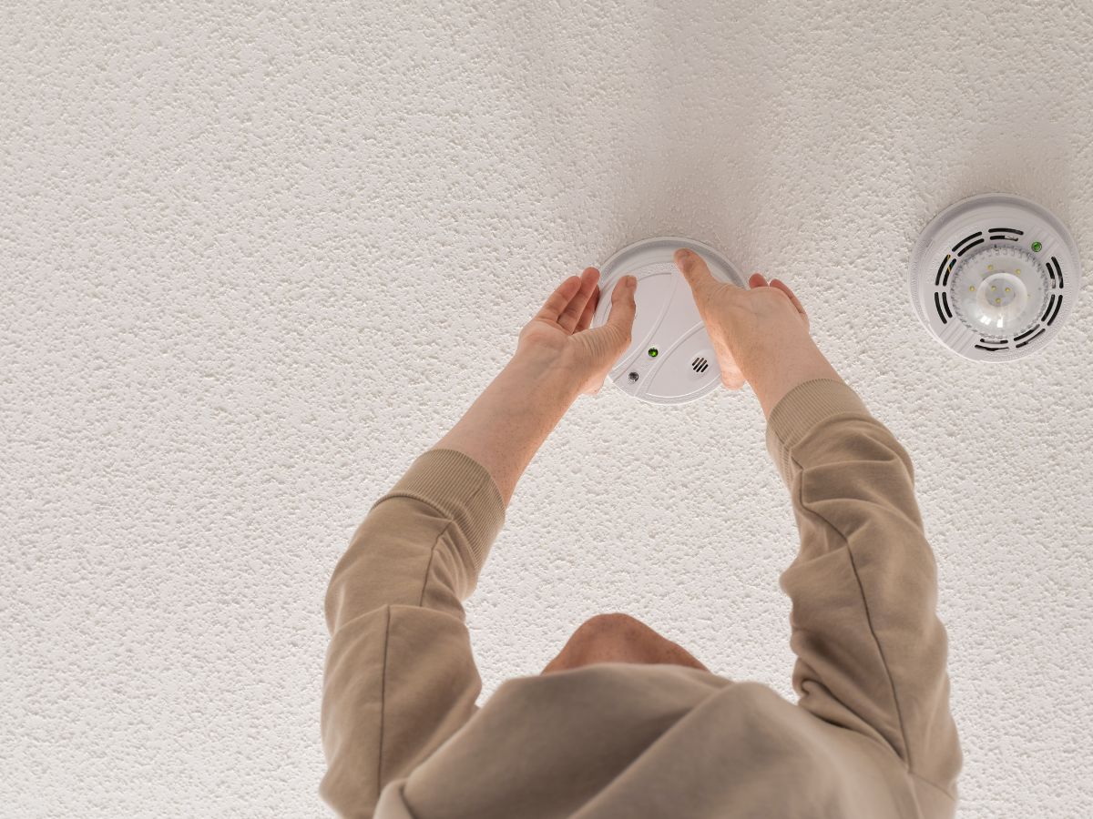 woman reaching for smoke alarm